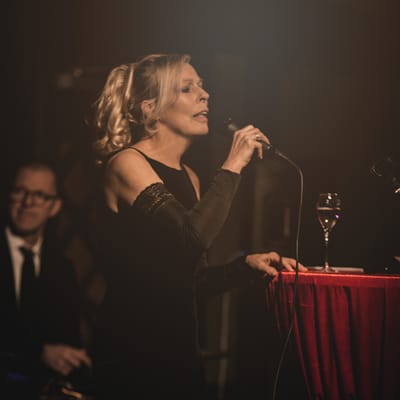 Gabriele Misch im schwarzen Kleid singt am Mikrofon